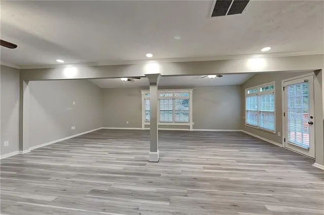 a view of empty room with wooden floor and fan