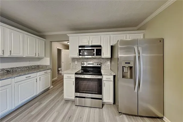 a kitchen with granite countertop a refrigerator stove and microwave
