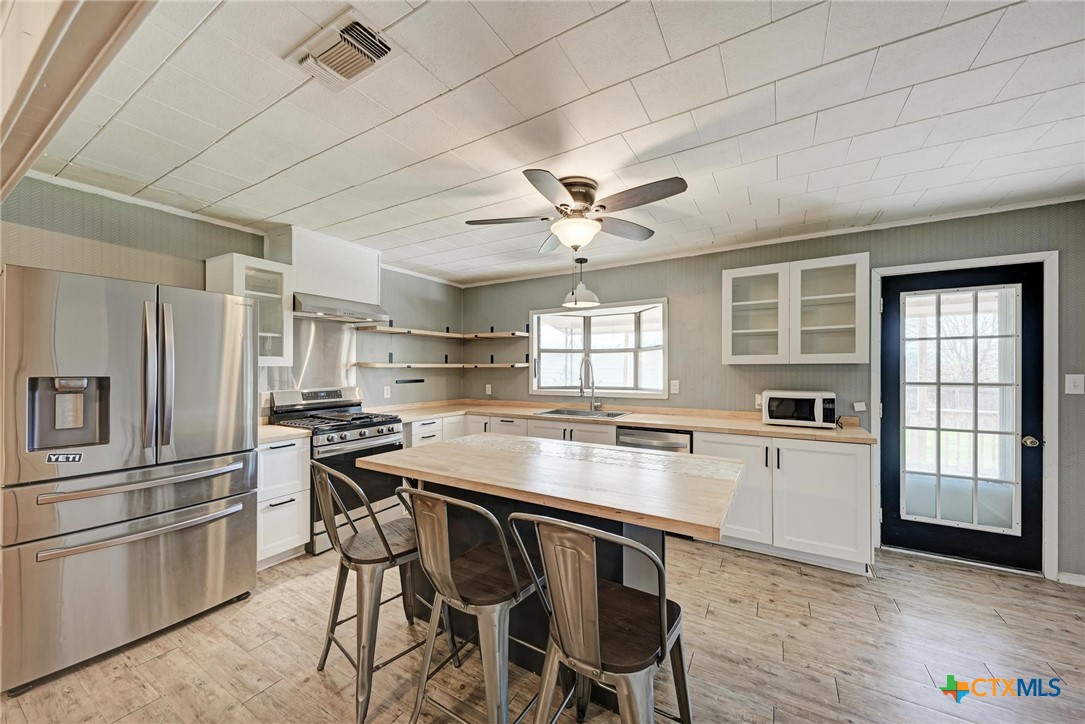 501 North Ridge Street Lampasas, TX 76550 - Photo 21 of 46 a kitchen with stainless steel appliances granite countertop a stove a refrigerator a sink a dining table and chairs with wooden floor
