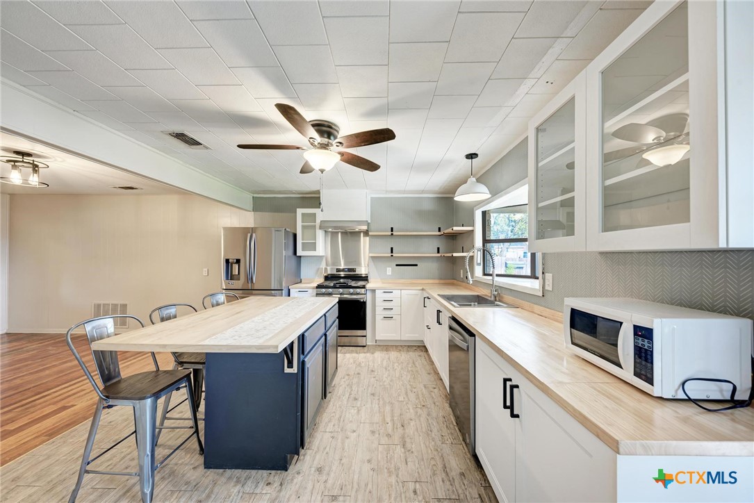 501 North Ridge Street Lampasas, TX 76550 - Photo 22 of 46 a large kitchen with a stove a sink dishwasher and a dining table with wooden floor