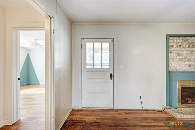 a view of a livingroom with wooden floor and a fireplace