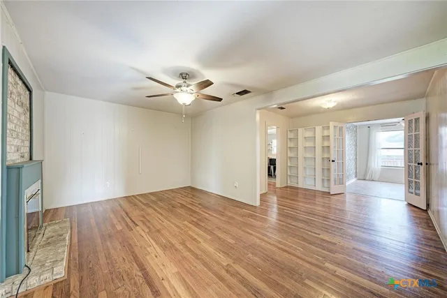 a view of an empty room with wooden floor and a window