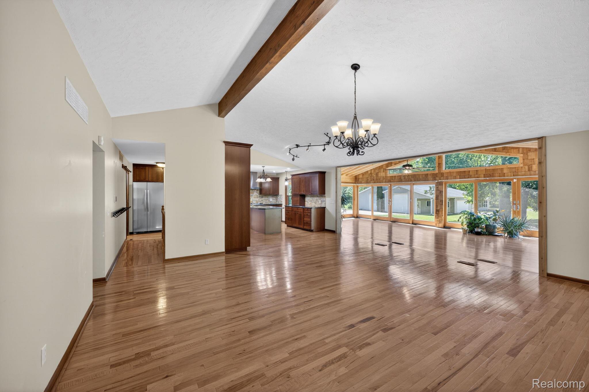 9353 Hill Road Swartz Creek, MI 48473 - Photo 30 of 98 Vaulted ceilings featuring exposed wood beams, wood-finish flooring, a chandelier lighting fixture, and a wall of windows