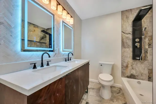 a bathroom with a bathtub shower sink mirror and toilet