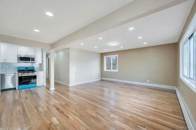 a view of an empty room with window and wooden floor