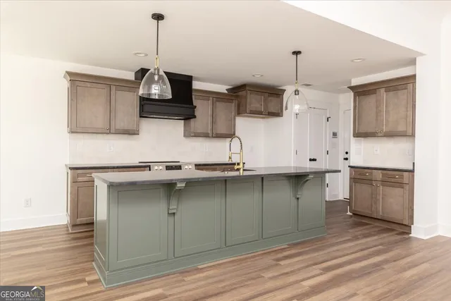 a kitchen with stainless steel appliances granite countertop a sink a stove and a wooden floors