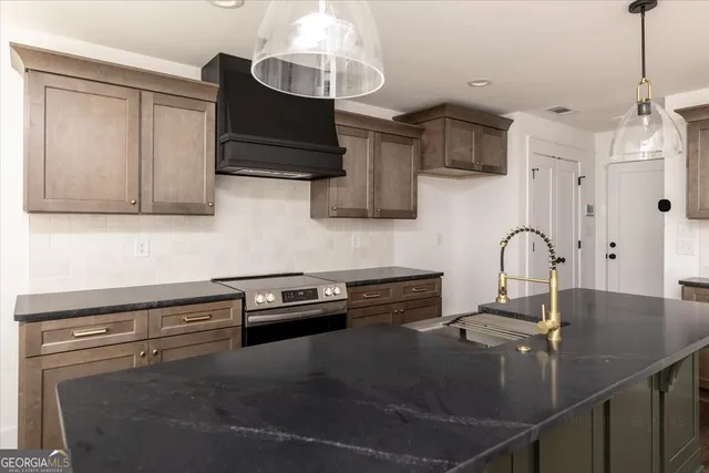 a kitchen with granite countertop a sink a stove and cabinets