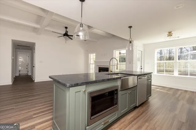 a kitchen with stainless steel appliances granite countertop a sink a stove and a wooden floors