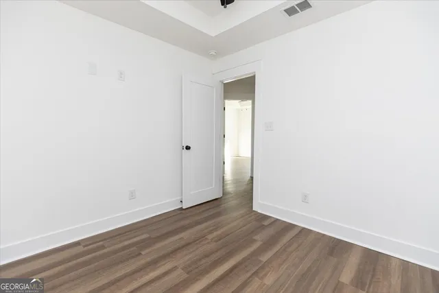 a view of an empty room with wooden floor and closet