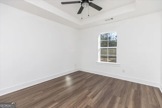 an empty room with wooden floor cabinet and windows