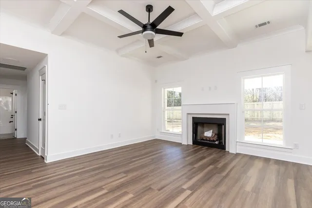 an empty room with wooden floor a fireplace a ceiling fan and a hardwood floor