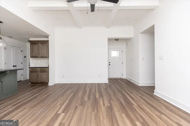 a view of kitchen and empty room with wooden floor