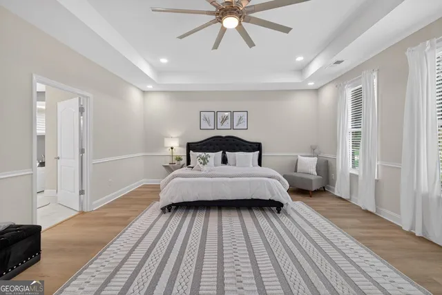 an empty room with wooden floor ceiling fan and windows