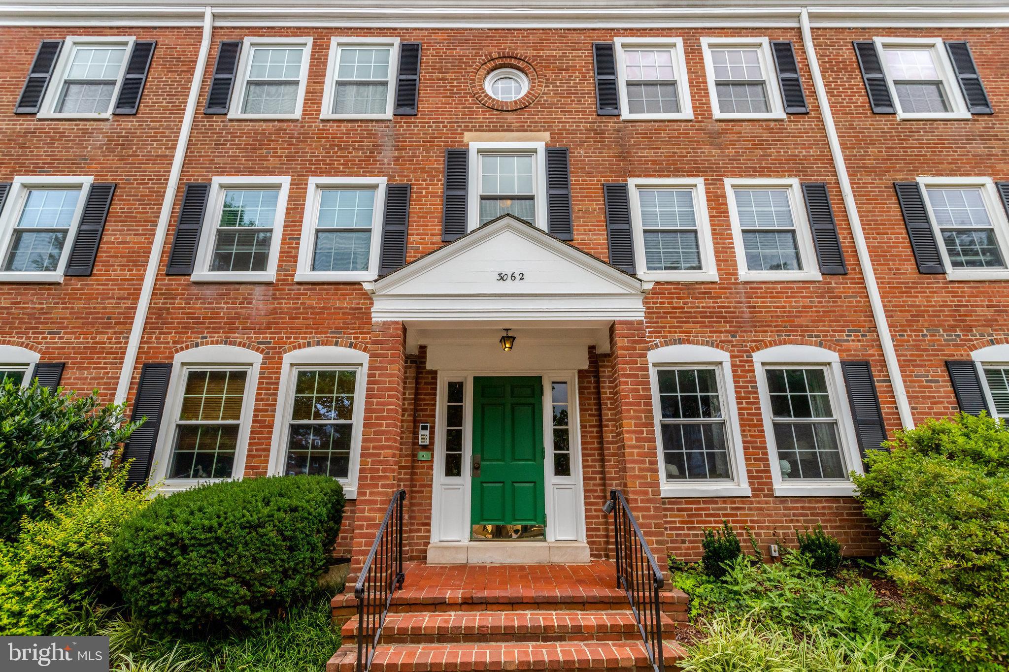 a front view of a brick house many windows and a large window