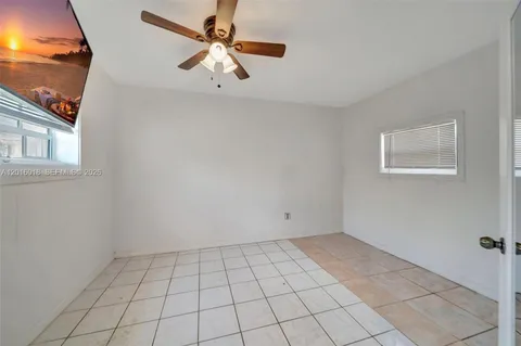 a view of an empty room with window and chandelier fan