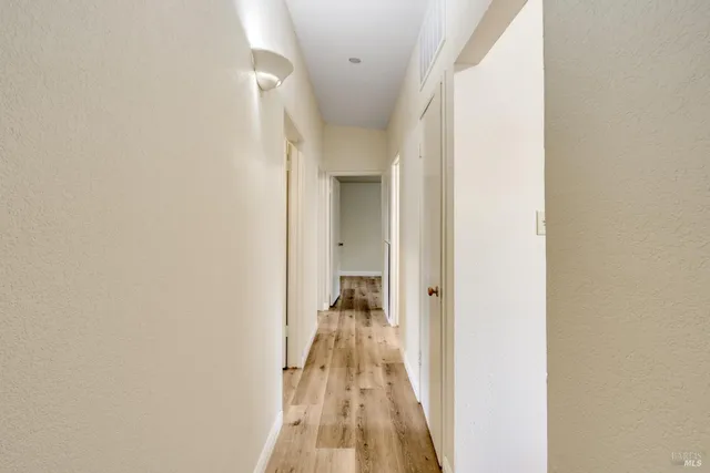 a view of a hallway with wooden floor and a bathroom