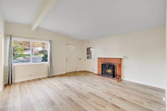 an empty room with wooden floor and fireplace