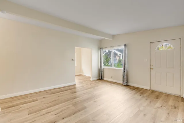a view of an empty room with wooden floor and a window