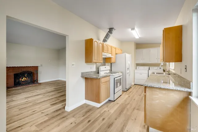 a large kitchen with stainless steel appliances granite countertop a sink dishwasher a stove and a wooden cabinets with wooden floor