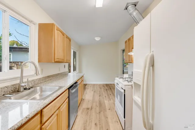 a kitchen with stainless steel appliances granite countertop a sink and a refrigerator