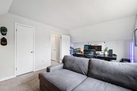 a living room with furniture a flat screen tv and a refrigerator