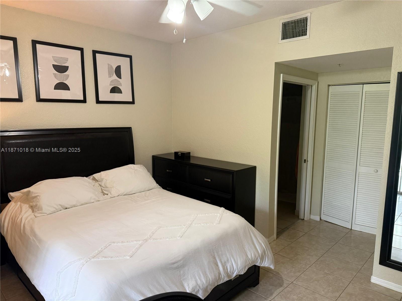 6876 West Sample Road, Unit 6876 Coral Springs, FL 33067 - Photo 22 of 27 a bedroom with a bed and painting on the wall