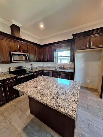 a kitchen with kitchen island granite countertop a sink stove and refrigerator