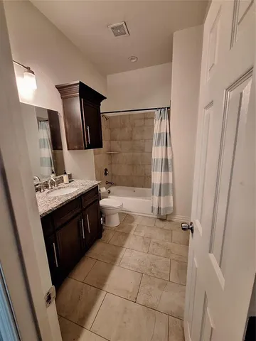 a bathroom with a tub sink vanity granite and shower