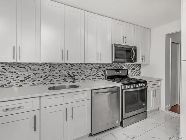 a kitchen with white cabinets sink and stainless steel appliances