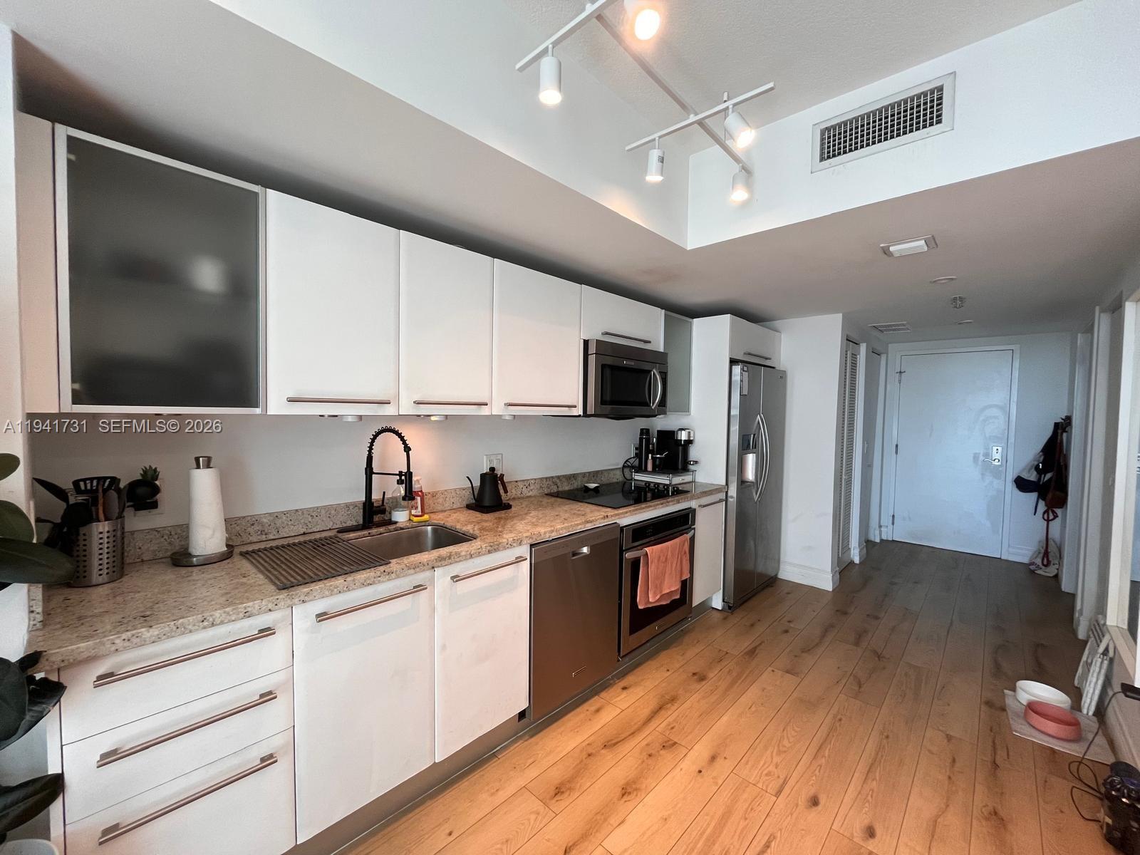 185 Southwest 7th Street, Unit 2006 Miami, FL 33130 - Photo 6 of 14 a kitchen with granite countertop a sink cabinets stainless steel appliances and wooden floor