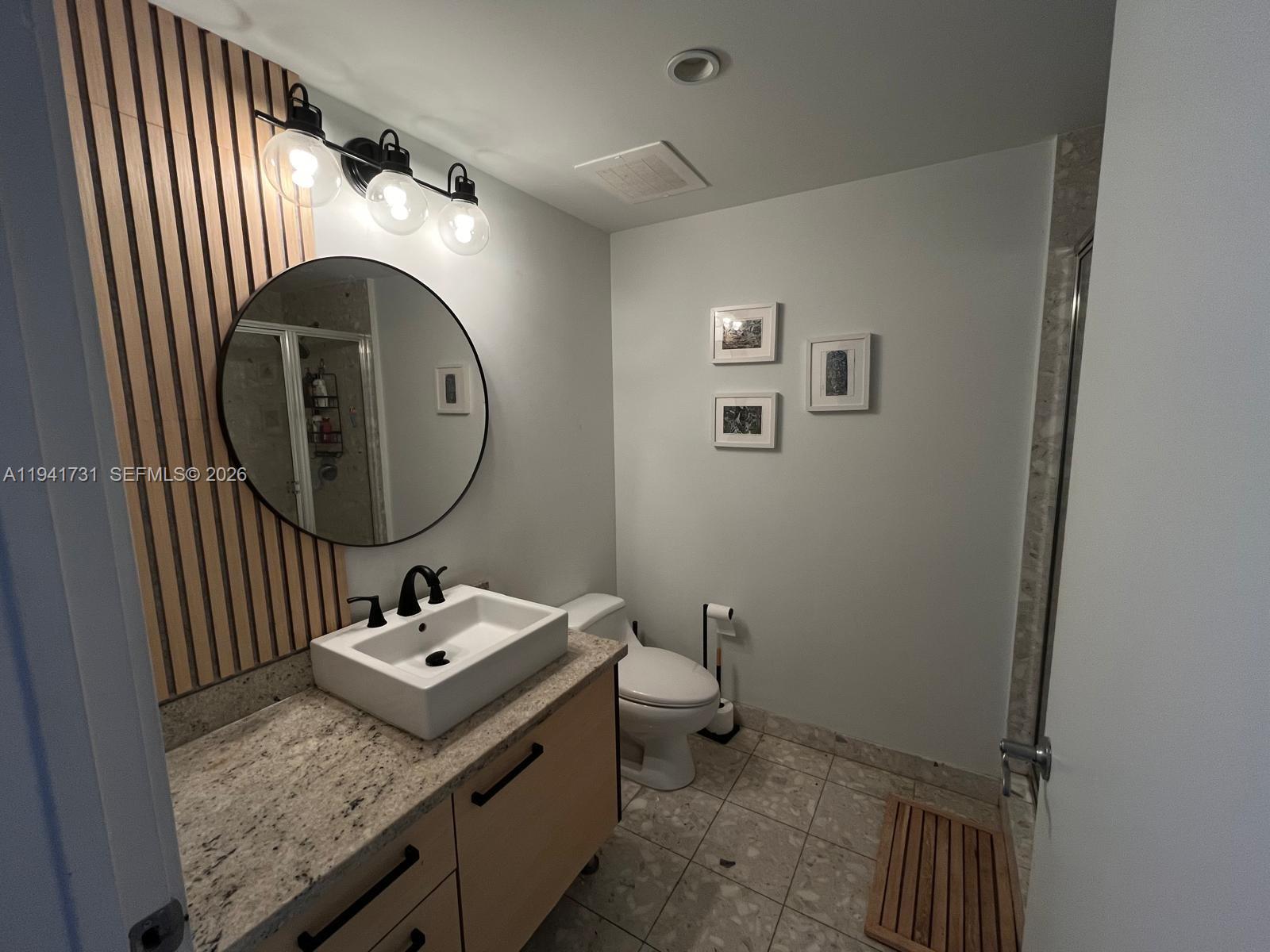 185 Southwest 7th Street, Unit 2006 Miami, FL 33130 - Photo 8 of 14 a bathroom with a granite countertop sink mirror vanity and toilet