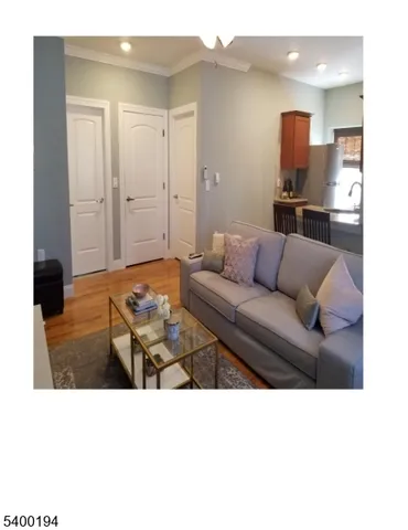 a living room with furniture and a walk in closet with wooden floor