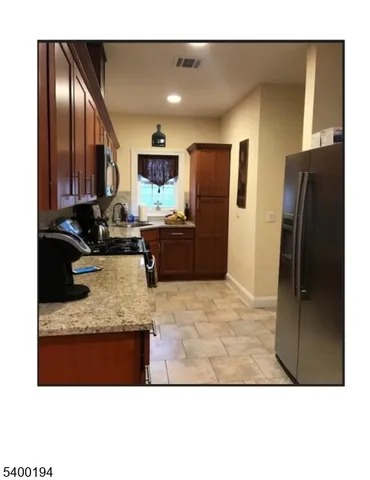 a kitchen with granite countertop a refrigerator and a sink