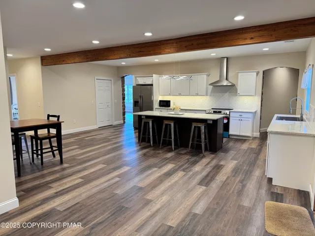 a large kitchen with kitchen island a wooden floor stainless steel appliances and dining table