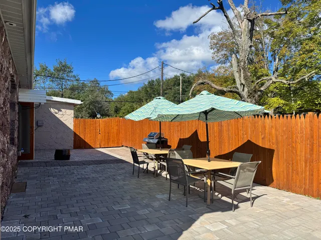 an outdoor sitting area with chairs and table under an umbrella