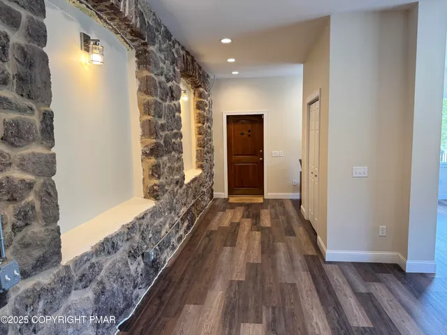 a view of a hallway with wooden floor and a bathroom