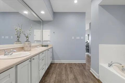 a spacious bathroom with a double vanity sink a mirror and a bathtub