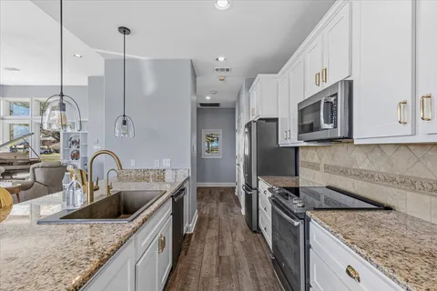 a kitchen with stainless steel appliances granite countertop a sink a stove and a wooden floors