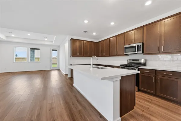 a kitchen with granite countertop wooden floors a stove and a microwave