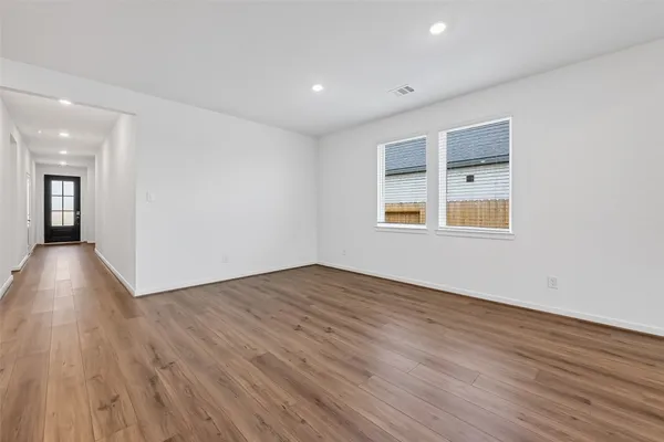 a view of an empty room with wooden floor and a window