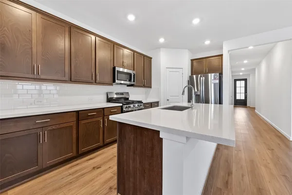 a kitchen with stainless steel appliances kitchen island granite countertop a stove a sink a refrigerator and cabinets