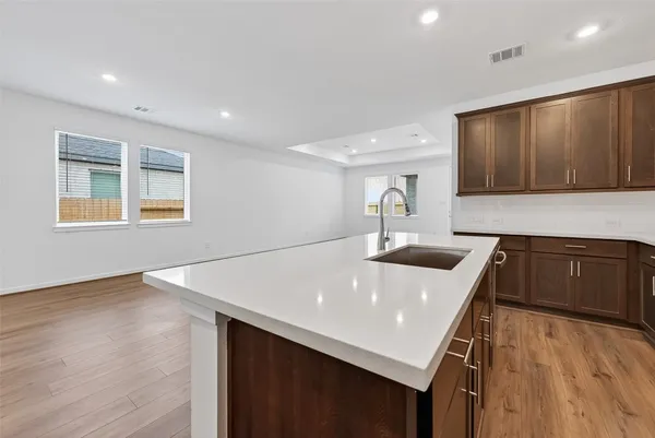 a kitchen with a sink and a stove top oven with wooden floor