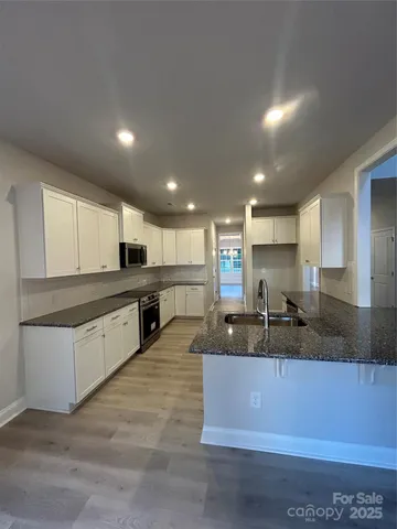 a large kitchen with a counter top space a sink stainless steel appliances and cabinets