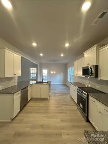 a large kitchen with stainless steel appliances granite countertop a large counter top a stove a sink and a refrigerator