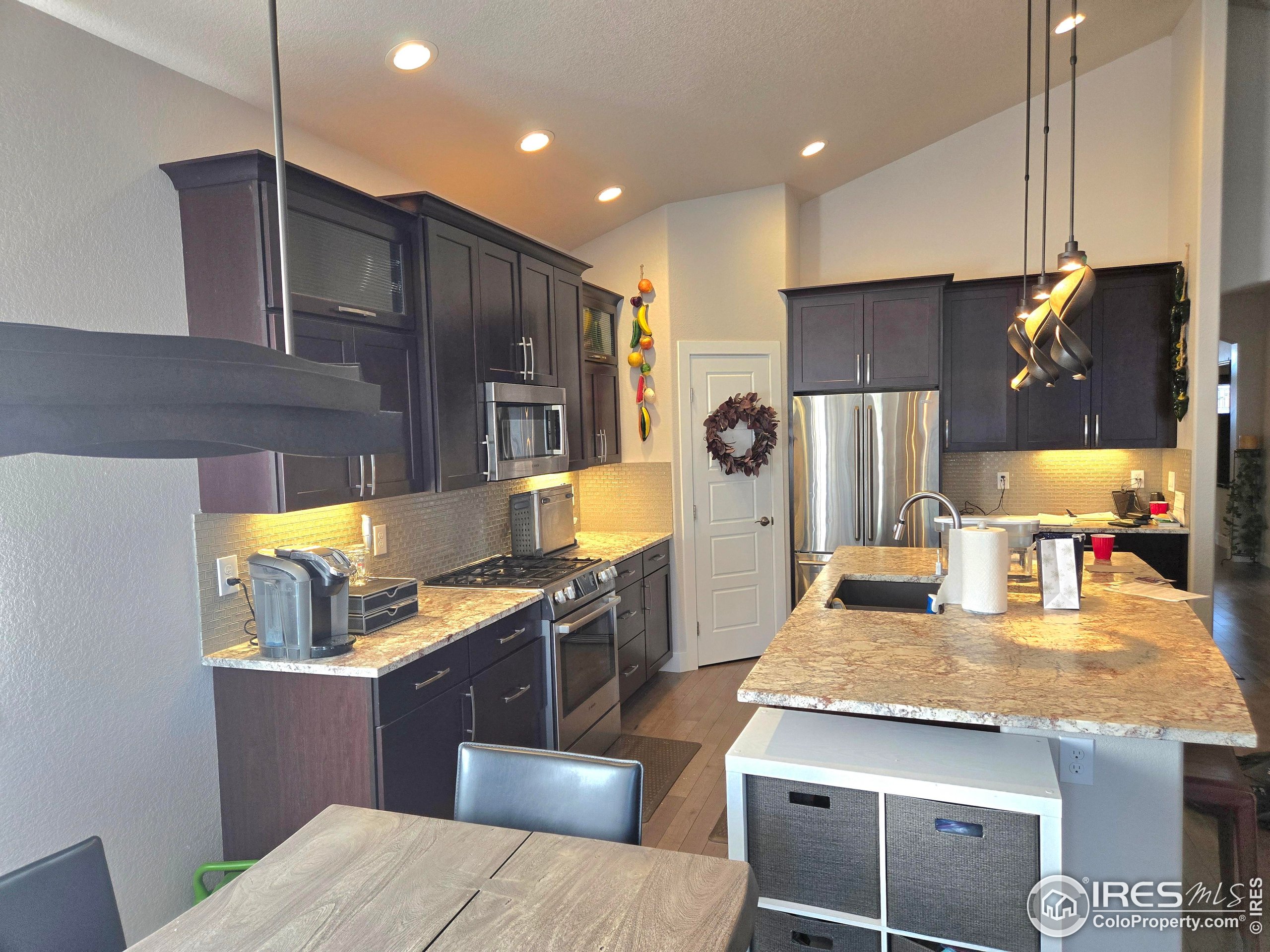 7292 McClellan Road Wellington, CO 80549 - Photo 16 of 19 a kitchen with kitchen island granite countertop wooden cabinets a stove and a refrigerator