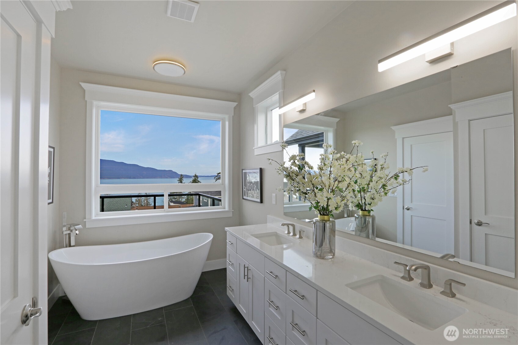 3706 West 3rd Street Anacortes, WA 98221 - Photo 37 of 40 a bathroom with a granite countertop tub a sink and mirror