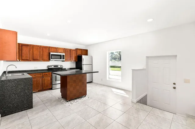a kitchen with stainless steel appliances granite countertop a stove a sink and a refrigerator