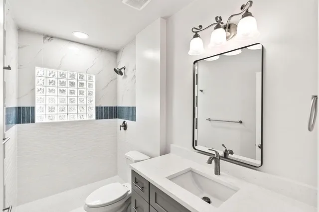 a bathroom with a sink a toilet and shower