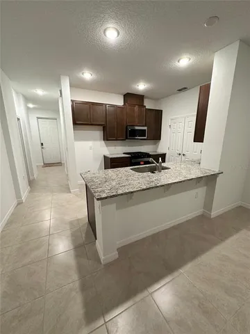 a large kitchen with a stove a sink a microwave a refrigerator and a counter top space