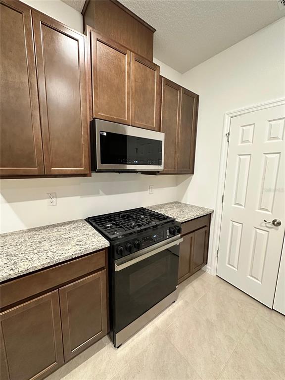 7004 Broad Wing Loop Howey-in-the-Hills, FL 34737 - Photo 3 of 10 a kitchen with granite countertop stainless steel appliances and cabinets